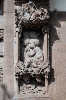Historical relief, façade section, stone carving depicting a mother and child with floral framing
