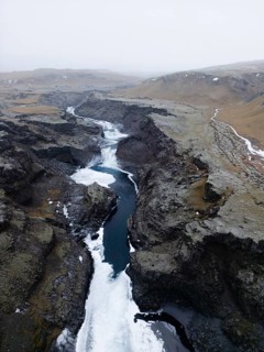 Aerial view of a serene Icelandic winter landscape, showcasing a winding river cutting through