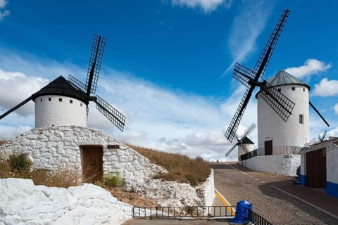Two windmills on a hill under a blue sky next to a path, Cueva de Mambrino, Craft Museum, left