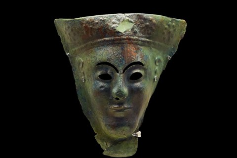 Hammered bronze mask of a wooden statuette, A mysterious ancient metal mask with greenish erosion,
