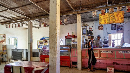 A rustic shop with a bar, posters on the walls and a relaxed atmosphere, a restaurant in a village