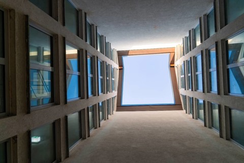 View upwards through a narrow courtyard with symmetrical windows and blue sky, Weil der Stadt,