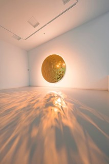 Golden mirror casts fascinating light reflections onto the floor of a modern art space, Schauwerk