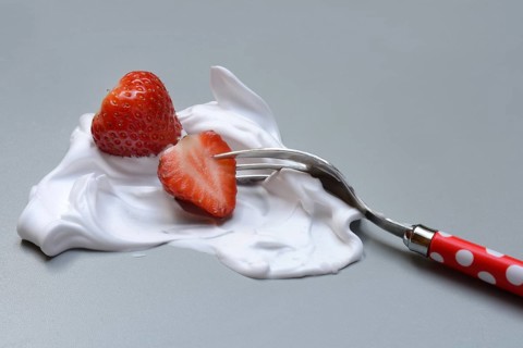 Strawberries on a fork with whipped cream
