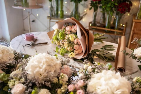 A stunning bouquet of fresh flowers, artistically arranged on a shop table, surrounded by greenery