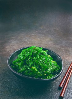 Chuka salad, made from fresh seaweed, with sesame dressing, served in a black bowl, with chopsticks