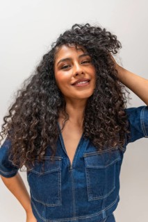 Vertical close-up portrait of a sensual latin woman hand on hair smiling at camera