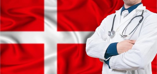 Denmark health care concept. Male doctor on Denmark flag. Doctor with crossed arms on Denmark flag
