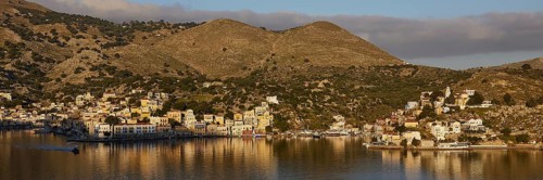Picturesque coastal view with hilly landscape and calm waters under clear skies, Symi Town, Symi,