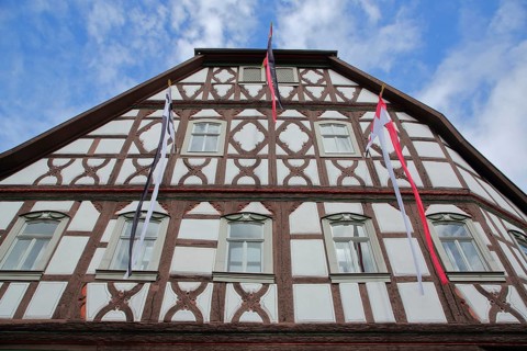 Historic half-timbered house Heimatspielhaus with flags, view from below, Münnerstadt, Rhön, Lower