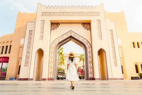 Doha Qatar Katara Cultural Village woman walking toward grand ornate archway gate traditional