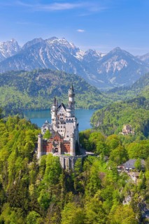 Neuschwanstein Castle with lake and mountains, surrounded by lush vegetation, Schwangau, Ostallgäu,
