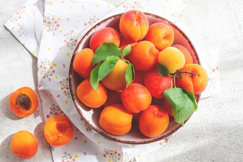 Fresh apricots in a bowl, on a bright table, natural light, top view, no people