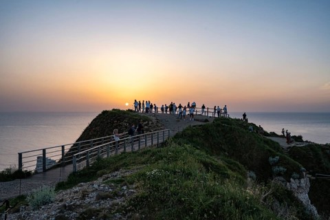Tourists stand on the observation deck of the Falaise d'Aval rock formation and tourist attraction