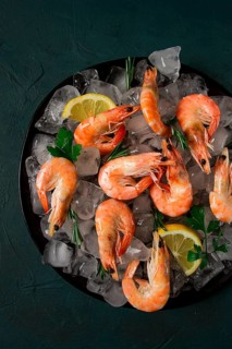 King shrimps, undivided, boiled-frozen, on ice, top view, selective focus, no people
