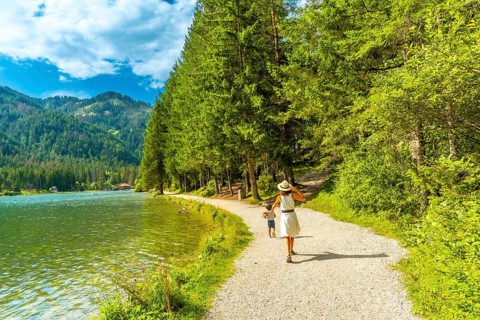 Tourists enjoying a walk along the scenic shores of lake dobbiaco, surrounded by the stunning