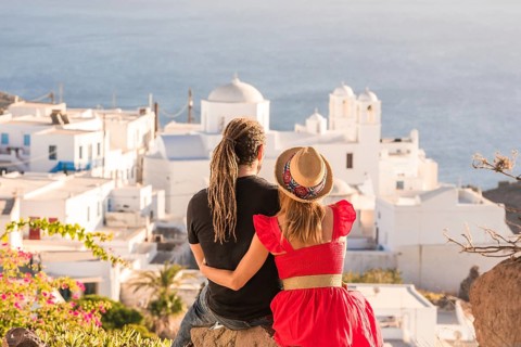 A couple embraces while admiring the stunning ocean view and traditional white architecture of