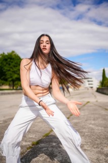 Vertical photo of a caucasian young beauty woman dancing energetically freestyle in an urban park