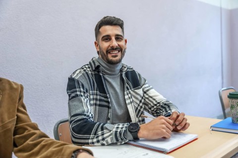 Smiling university student engaging in studying and taking notes during a lecture, immersed in