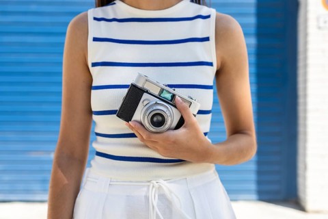 A woman enjoys city life holding a vintage camera, embracing the freedom and creativity of outdoor