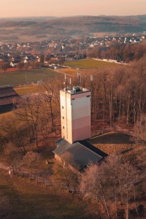 Water towerA tower rises from a wooded area near a village, landscape in cool pastel colors and