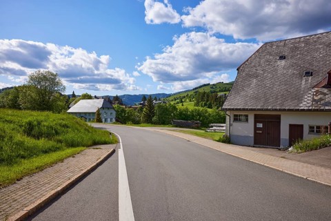 Street and houses with a view of the landscape under a blue sky with cumulus clouds in the