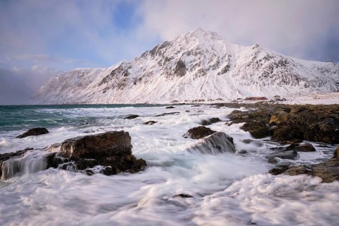 Beach of Norwegian sea on rocky coast in fjord on sunset in winter. Vareid beach, Lofoten islands,