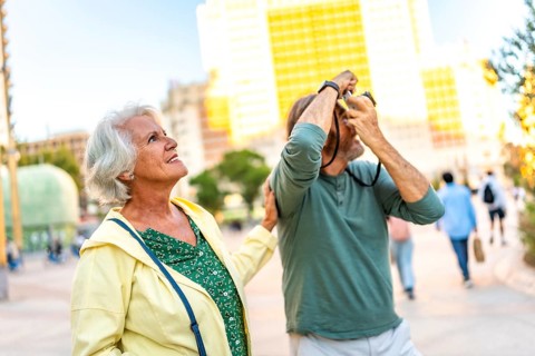 Senior man talking a photo with a digital camera while visiting the city with his partner