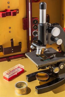 Vintage black Bausch & Lomb research microscope with objective lenses in front of opened brownish