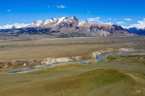 River flows in a canyon in front of snow-capped volcanic mountains, between Chile Chico and