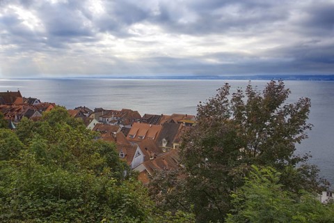 View of the houses in the old town of Meersburg with red tiled roofs. Behind it, Lake Constance