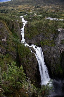 High waterfall that stretches through a narrow, tree-lined gorge, Voringsfossen, with a drop height