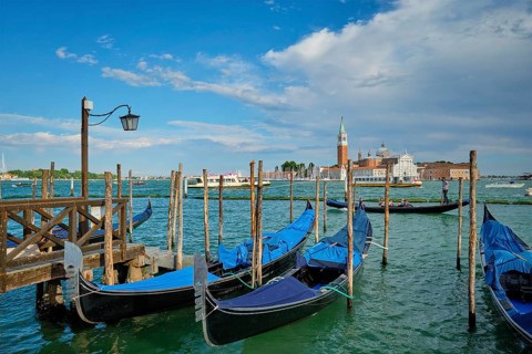 VENICE, ITALY, JUNE 27, 2018: Gondolas and gondolier in lagoon of Venice by Saint Mark (San Marco)