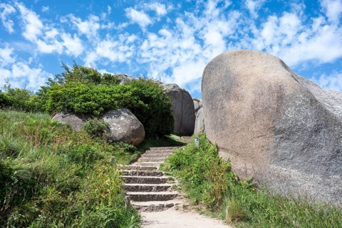 A stone staircase snakes through monumental pink granite rock formations cut around by nature on a