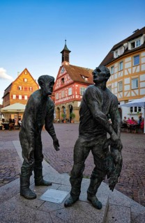 Bronze figures, sculptures The Pigeon Houses by Henning Seemann, half-timbered houses behind them,