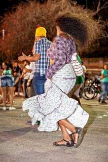 Woman with waving hair dances happily at night among people outdoors, joy and dancing at a festival