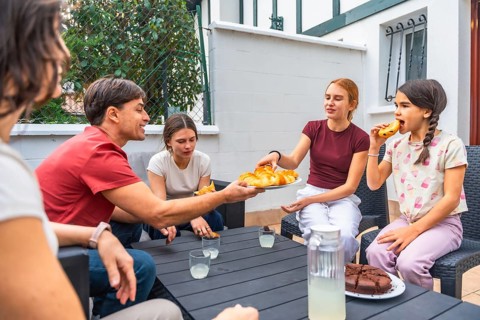 Family members are gathering on an outdoor patio, enjoying snack time together while sharing
