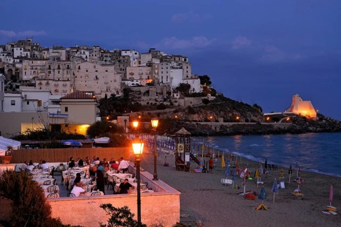 Terrace of a Ristorante Pizzeria at the beach Lido di Fondi, rocky outcrop with historical fortress