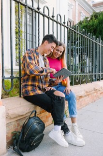 A happy lesbian couple enjoys a joyful moment together, sharing a laugh while looking at a tablet.