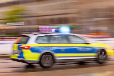 A police car on an emergency drive on Wilsdruffer Straße at Altmarkt with flashing blue lights,