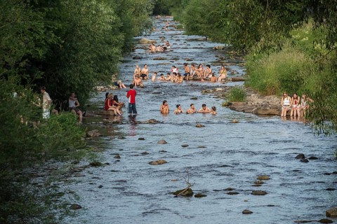 Young people sitting by and in the river, bathing in the city, heat, heat wave, climate change,