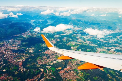 Aerial commercial aircraft passenger window seat point of view on take off. Airplane wing above