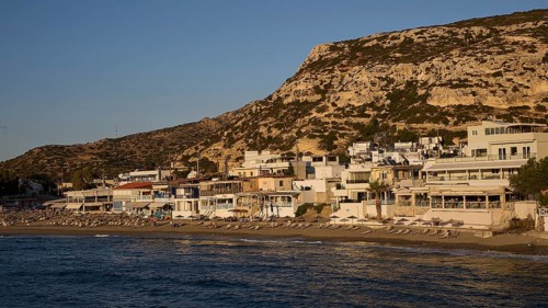 Coastal town with buildings on the beach, illuminated by the golden light of the evening, Matala,