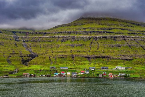 Little village on the foot of a the cliffs in Estuyroy, Faroe islands, Denmark