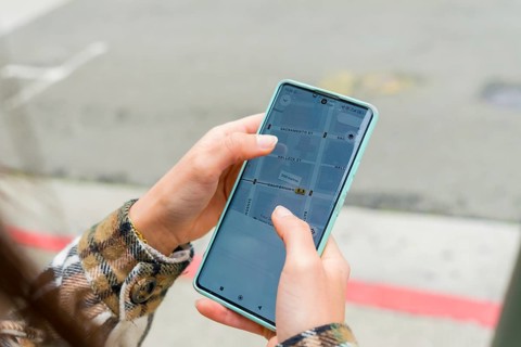 Person holding smartphone showing gps navigation app with san francisco street map, finding route