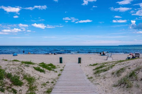 Wooden jetty leads to the quiet beach with blue sea and scattered people, Juliusruh, Breege, Rügen,