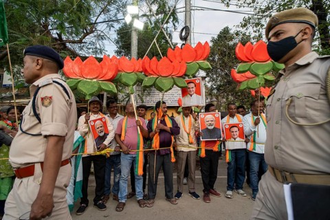 Supporters hold lotus symbols and placards featuring Narendra Modi during a public rally of the