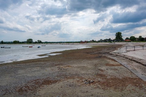 A wide beach under a cloudy sky, boats are visible in the distance, Hohwacht, Schleswig-Holstein,