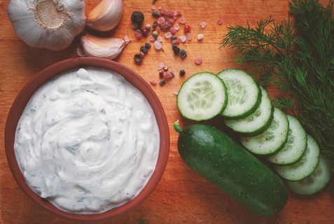 Greek zajiki sauce, in a clay bowl, on a wooden board, with ingredients, top view, no people