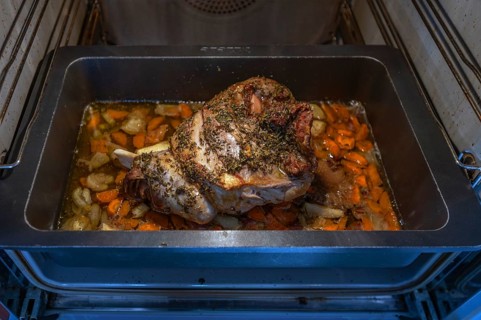 Finished roast wild boar with spices and vegetables in a cast-iron casserole in the oven, Bavaria,